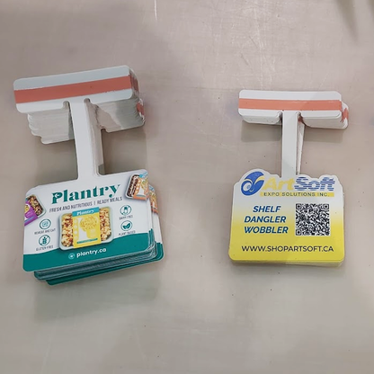 Close-up of the mounting tab on a shelf dangler featuring pre-applied double-sided tape.